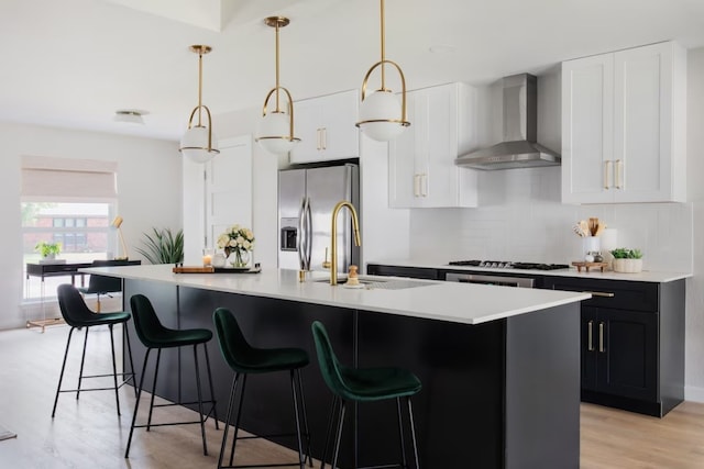2608 Coatbridge Dr, Austin, TX 78745 - kitchen with wall chimney range hood, stainless steel fridge with ice dispenser, light countertops, gas stovetop, and a center island with sink