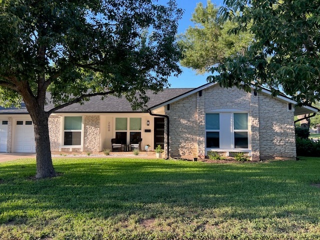 2608 Coatbridge Dr, Austin, TX 78745 - view of front of home with stone siding, a front yard, a garage, and concrete driveway