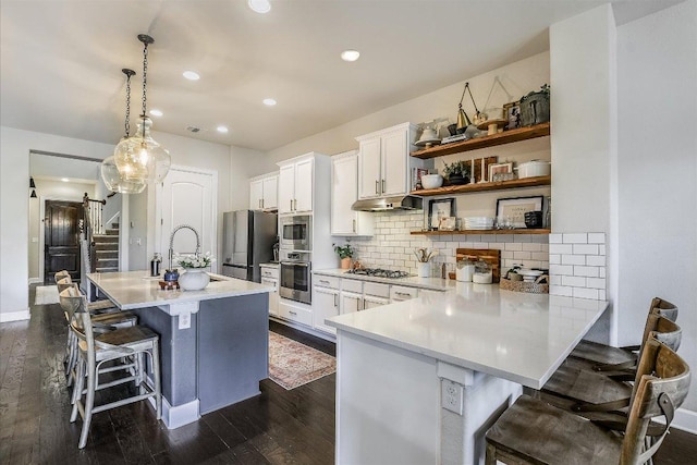 340 Fort Cobb Way, Georgetown, TX 78628 - kitchen with appliances with stainless steel finishes, a kitchen bar, white cabinets, dark wood-type flooring, and light countertops
