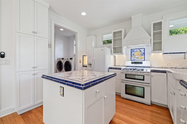 1114 Reagan Ter, Austin, TX 78704 - kitchen with double oven range, white fridge with ice dispenser, washer and clothes dryer, custom range hood, and white cabinetry