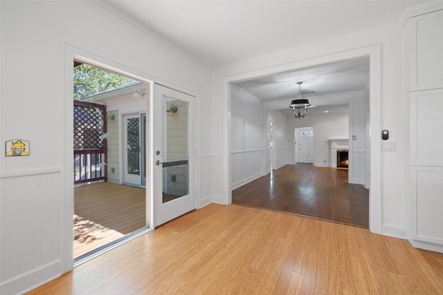 1114 Reagan Ter, Austin, TX 78704 - unfurnished dining area featuring light wood-style floors, a decorative wall, wainscoting, a chandelier, and a warm lit fireplace
