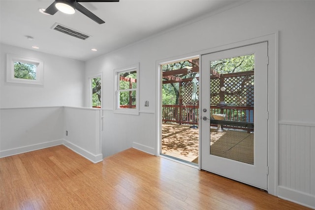 1114 Reagan Ter, Austin, TX 78704 - doorway to outside featuring light wood-style flooring, plenty of natural light, ceiling fan, a wainscoted wall, and crown molding