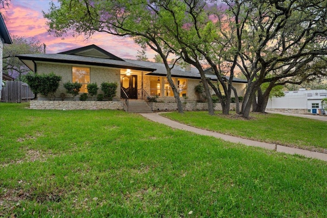 ranch-style house featuring a front yard, fence, and brick siding