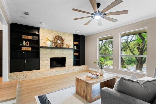 living room featuring a fireplace, a ceiling fan, visible vents, wood finished floors, and built in shelves
