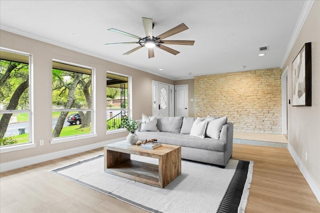 living room with a wealth of natural light, visible vents, light wood-type flooring, and a ceiling fan