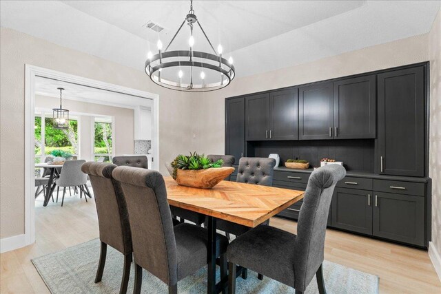 dining space featuring a notable chandelier, visible vents, light wood-type flooring, and lofted ceiling