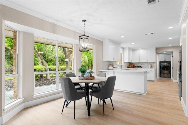 dining space featuring washer / clothes dryer, light wood-style floors, ornamental molding, and visible vents