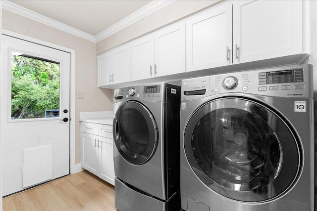 washroom with light wood-style flooring, crown molding, cabinet space, and washer and clothes dryer