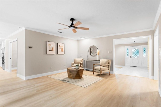 living area featuring visible vents, baseboards, a ceiling fan, crown molding, and light wood-style flooring