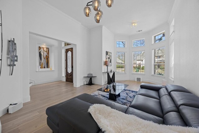 1409 Vibar Cv, Round Rock, TX 78681 - living room with light wood finished floors, a chandelier, crown molding, and a towering ceiling