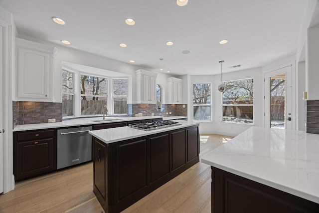 1409 Vibar Cv, Round Rock, TX 78681 - kitchen with appliances with stainless steel finishes, light wood-style floors, recessed lighting, white cabinetry, and tasteful backsplash