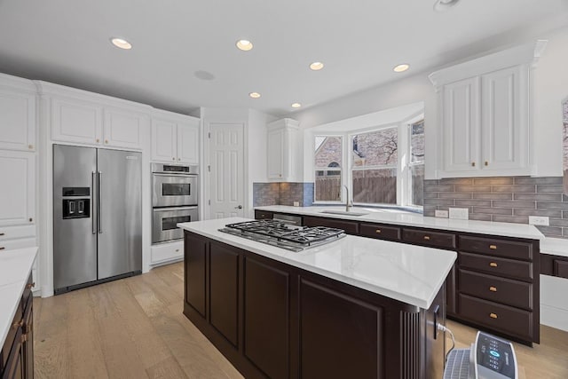 1409 Vibar Cv, Round Rock, TX 78681 - kitchen featuring stainless steel appliances, white cabinets, light wood-style flooring, backsplash, and recessed lighting