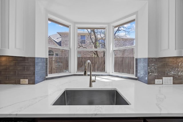 1409 Vibar Cv, Round Rock, TX 78681 - kitchen featuring light stone countertops, decorative backsplash, and white cabinetry