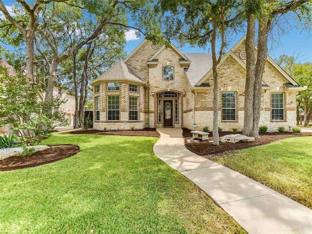 1409 Vibar Cv, Round Rock, TX 78681 - french provincial home with brick siding, a front yard, a shingled roof, and stone siding
