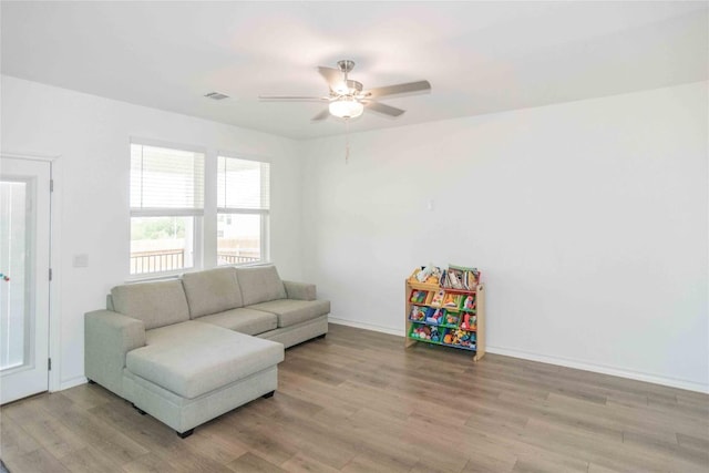 living area with visible vents, light wood finished floors, baseboards, and a ceiling fan