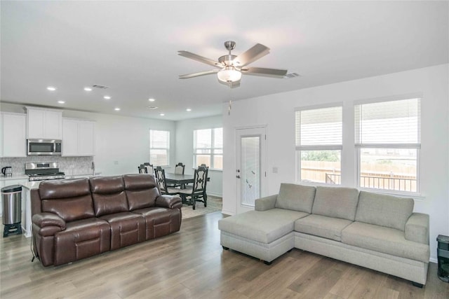 living area with ceiling fan, recessed lighting, visible vents, and light wood-style flooring