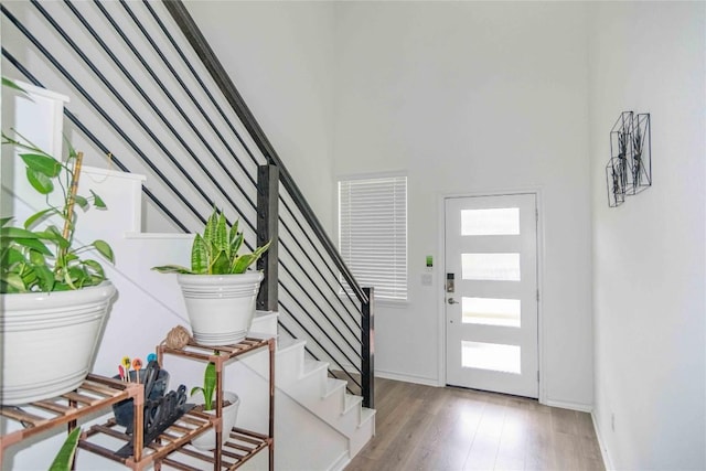 entryway with stairway, a high ceiling, baseboards, and light wood-type flooring