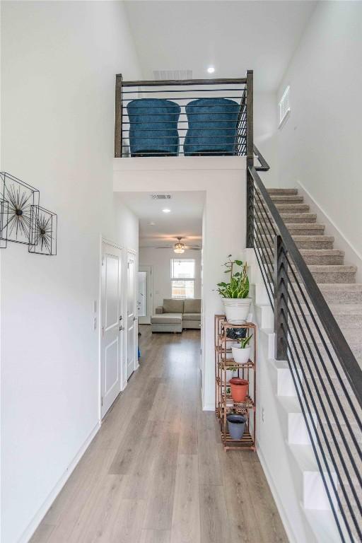 entrance foyer with a high ceiling, visible vents, baseboards, light wood-style flooring, and stairs