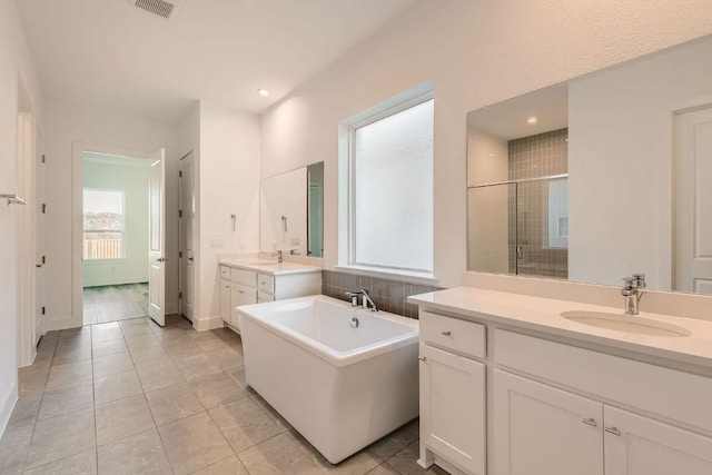 300 Alava Way, Georgetown, TX 78628 - bathroom featuring two vanities, a freestanding tub, a stall shower, recessed lighting, and tile patterned flooring
