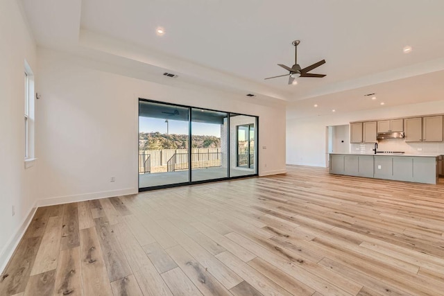 300 Alava Way, Georgetown, TX 78628 - unfurnished living room with ceiling fan, light wood finished floors, a tray ceiling, and recessed lighting