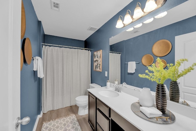 bathroom featuring vanity, visible vents, toilet, and wood finished floors