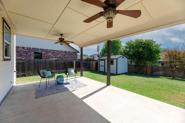 view of patio with an outbuilding, ceiling fan, a fenced backyard, and a storage unit