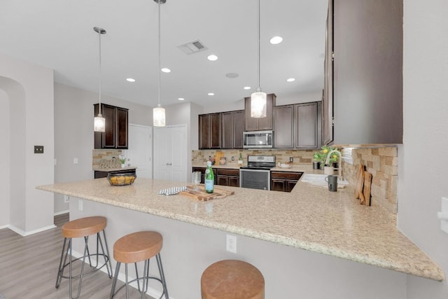 1114 Sussex Pl, Round Rock, TX 78665 - kitchen featuring appliances with stainless steel finishes, dark brown cabinets, light wood-style flooring, a peninsula, and recessed lighting