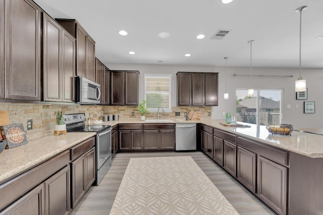 1114 Sussex Pl, Round Rock, TX 78665 - kitchen featuring stainless steel appliances, a peninsula, recessed lighting, dark brown cabinets, and backsplash