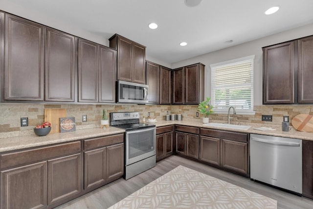 kitchen with a sink, light countertops, dark brown cabinets, stainless steel appliances, and backsplash