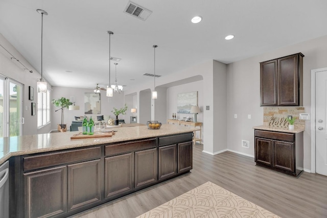 1114 Sussex Pl, Round Rock, TX 78665 - kitchen with dark brown cabinets, light wood-style flooring, backsplash, hanging light fixtures, and recessed lighting