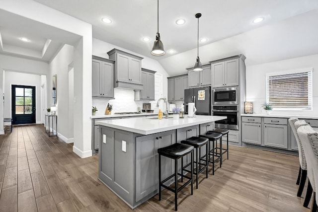 2831 Tanager Trce, Katy, TX 77493 - kitchen featuring appliances with stainless steel finishes, gray cabinets, wood finished floors, recessed lighting, and lofted ceiling