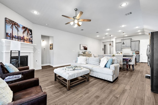 2831 Tanager Trce, Katy, TX 77493 - living room featuring ceiling fan, light wood finished floors, recessed lighting, and a glass covered fireplace