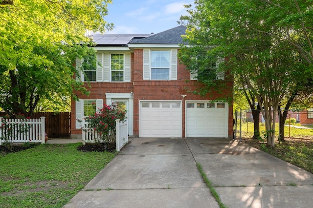 view of front of house featuring driveway, brick siding, fence, solar panels, and a garage