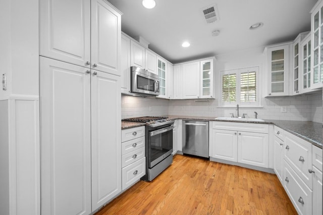 kitchen with stainless steel appliances, a sink, white cabinetry, tasteful backsplash, and recessed lighting