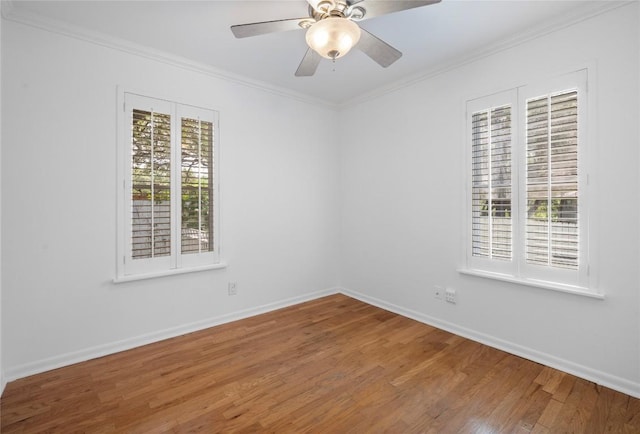 empty room with ornamental molding, wood finished floors, baseboards, and ceiling fan