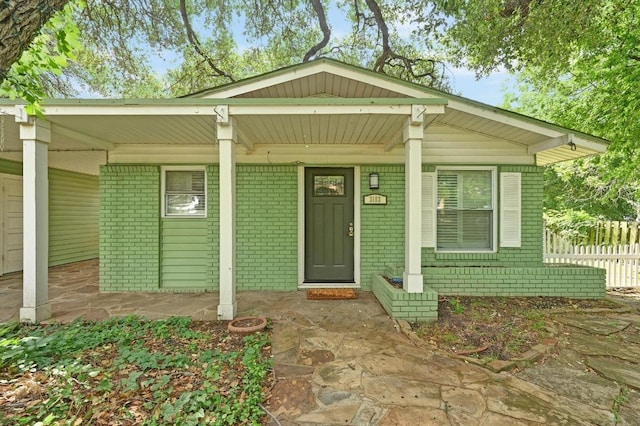 view of front of property with brick siding, fence, and a porch