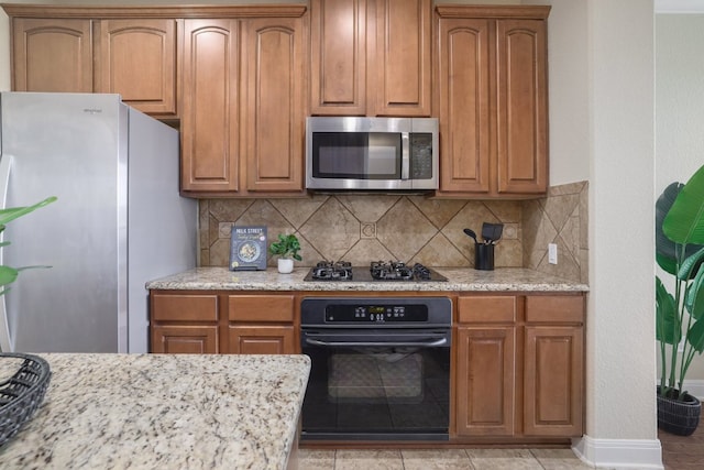 103 Aria Rdg Unit 902, Austin, TX 78738 - kitchen with appliances with stainless steel finishes, decorative backsplash, brown cabinets, and light stone counters