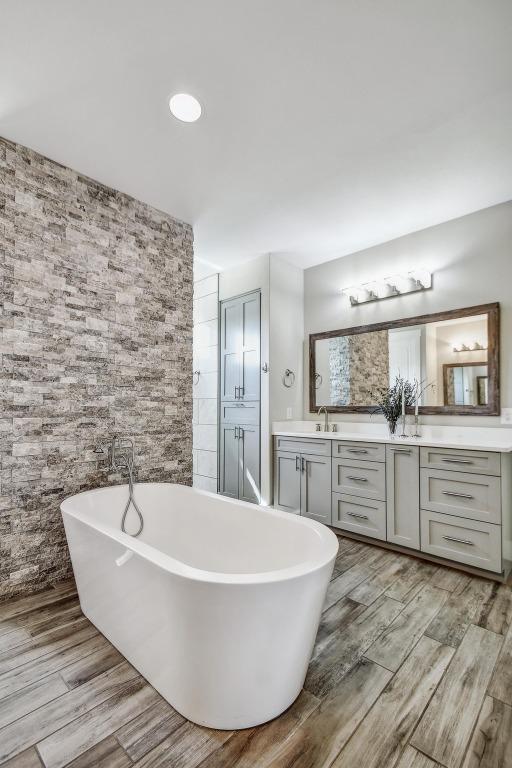 1609 Havenwood Blvd, New Braunfels, TX 78132 - full bath with double vanity, a soaking tub, and wood finished floors