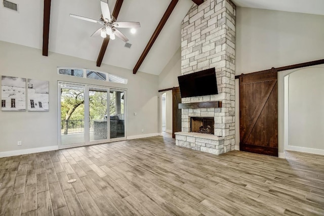 1609 Havenwood Blvd, New Braunfels, TX 78132 - unfurnished living room with a barn door, high vaulted ceiling, a ceiling fan, wood finished floors, and beam ceiling
