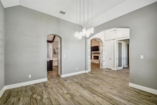 1609 Havenwood Blvd, New Braunfels, TX 78132 - unfurnished room featuring wood finished floors, a fireplace, baseboards, high vaulted ceiling, and arched walkways