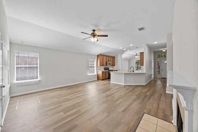 806 Broken Trace Ct, Round Rock, TX 78665 - unfurnished living room with ceiling fan, baseboards, light wood-type flooring, lofted ceiling, and a sink