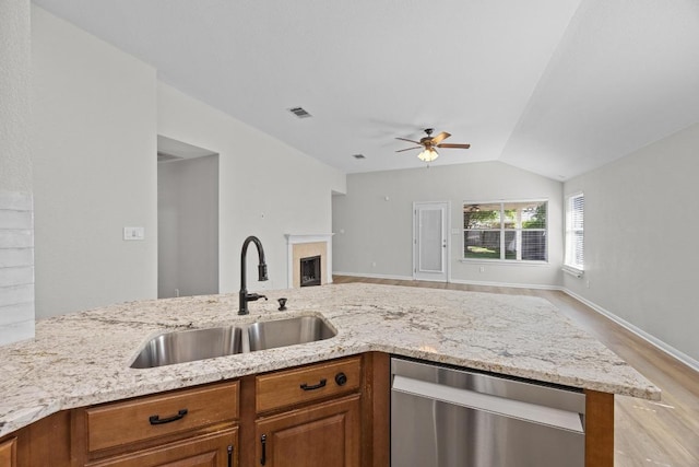 806 Broken Trace Ct, Round Rock, TX 78665 - kitchen featuring stainless steel dishwasher, a sink, light stone countertops, brown cabinetry, and vaulted ceiling