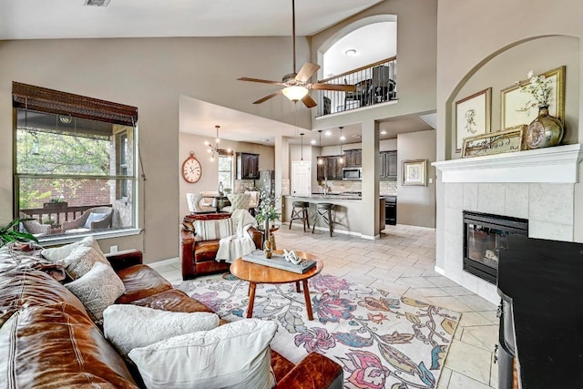 21940 Agarito Ln, Spicewood, TX 78669 - living room with a ceiling fan, light tile patterned flooring, a fireplace, high vaulted ceiling, and baseboards
