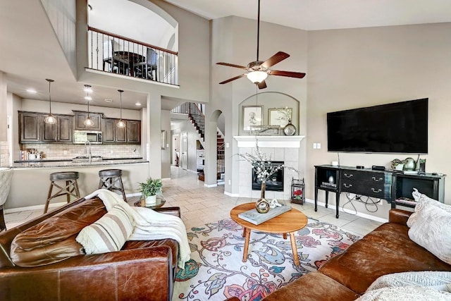 21940 Agarito Ln, Spicewood, TX 78669 - living area featuring a ceiling fan, arched walkways, baseboards, and a tiled fireplace