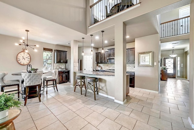 21940 Agarito Ln, Spicewood, TX 78669 - kitchen featuring stainless steel microwave, a chandelier, tasteful backsplash, light tile patterned flooring, and a breakfast bar