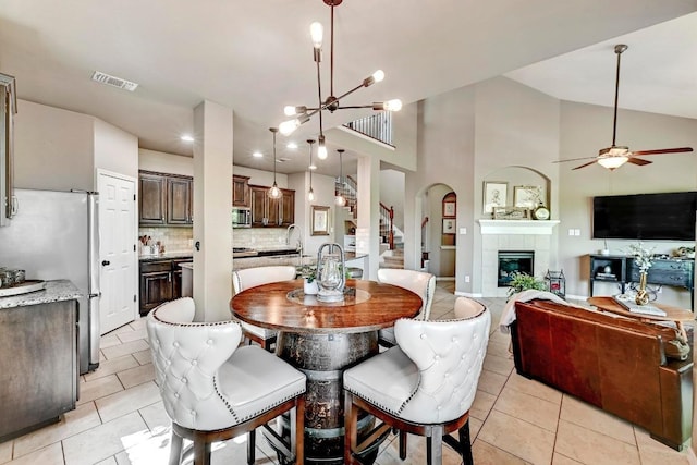 21940 Agarito Ln, Spicewood, TX 78669 - dining space with light tile patterned floors, a tile fireplace, a ceiling fan, a chandelier, and recessed lighting