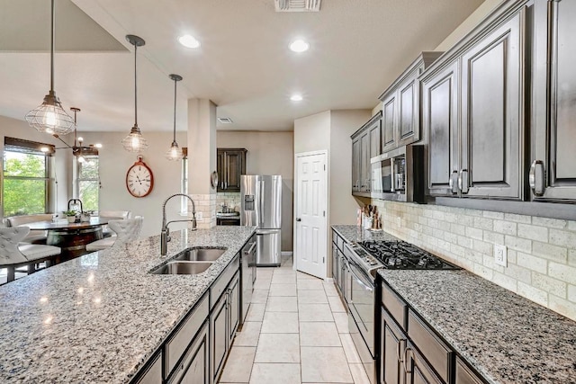 21940 Agarito Ln, Spicewood, TX 78669 - kitchen featuring appliances with stainless steel finishes, a sink, backsplash, light stone countertops, and pendant lighting