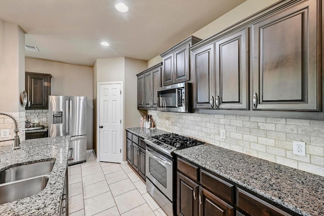 21940 Agarito Ln, Spicewood, TX 78669 - kitchen featuring appliances with stainless steel finishes, a sink, decorative backsplash, light stone counters, and light tile patterned floors