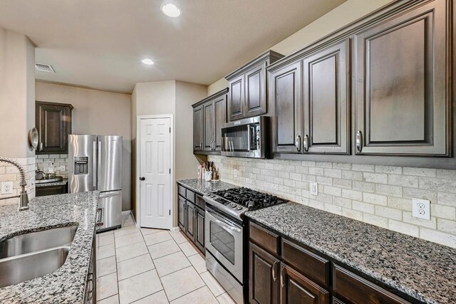 21940 Agarito Ln, Spicewood, TX 78669 - kitchen with stainless steel appliances, a sink, backsplash, light stone counters, and light tile patterned floors