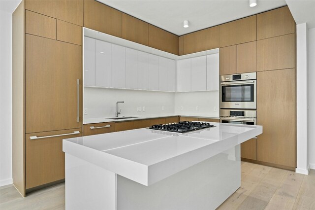 313 W 17th St Unit 2403, Austin, TX 78701 - kitchen featuring light wood-type flooring, gas stovetop, a sink, and double oven